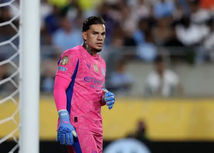 Bramkarz Manchester City w różowym stroju, gotowy do obrony bramki.